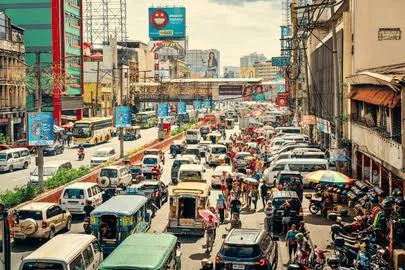A busy street in Metro Manila lined with jeepneys, cars and shopfronts.